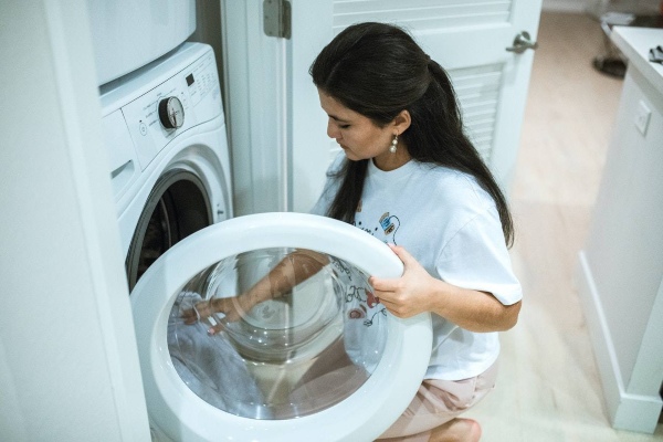 Mujer poniendo la lavadora con más carga de la recomendada.