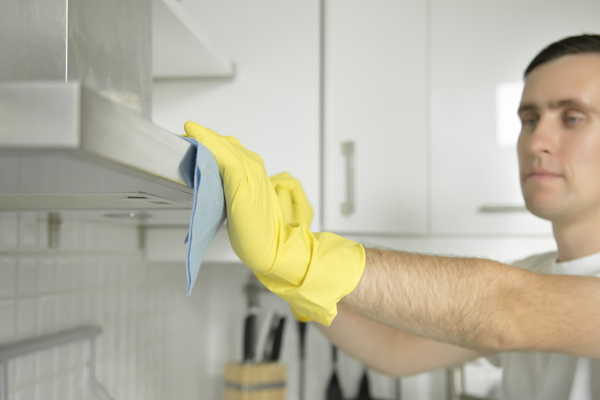 Hombre limpiando la campana extractora de su cocina